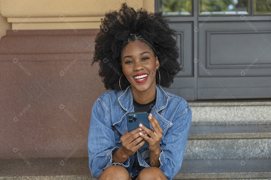 Linda mulher jovem negra cabelo afro mexendo em seu celular