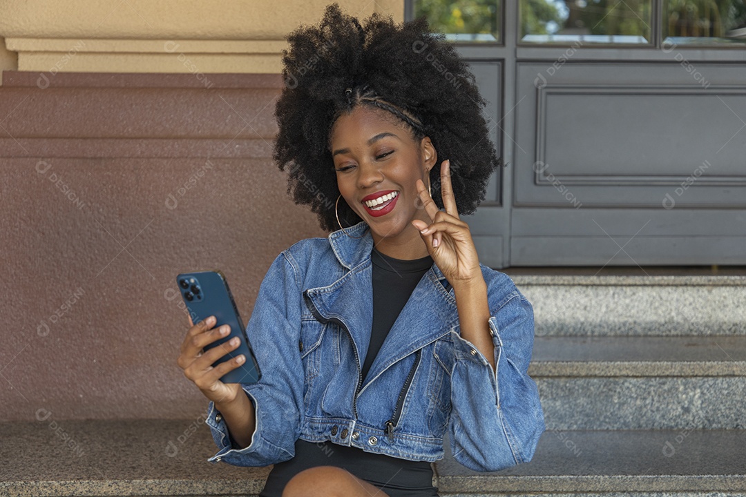 Linda mulher jovem negra cabelo afro mexendo em seu celular