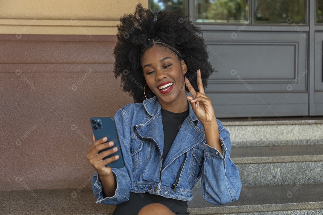 Linda mulher jovem negra cabelo afro mexendo em seu celular