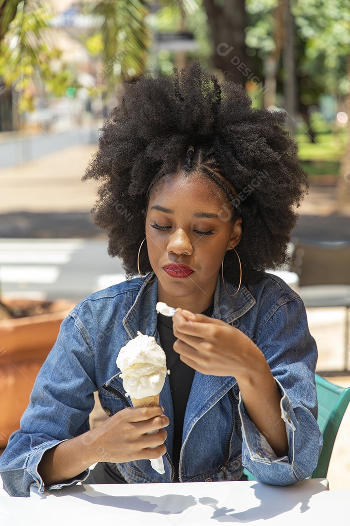 Linda mulher jovem negra cabelo afro cacheado tomando sorvete
