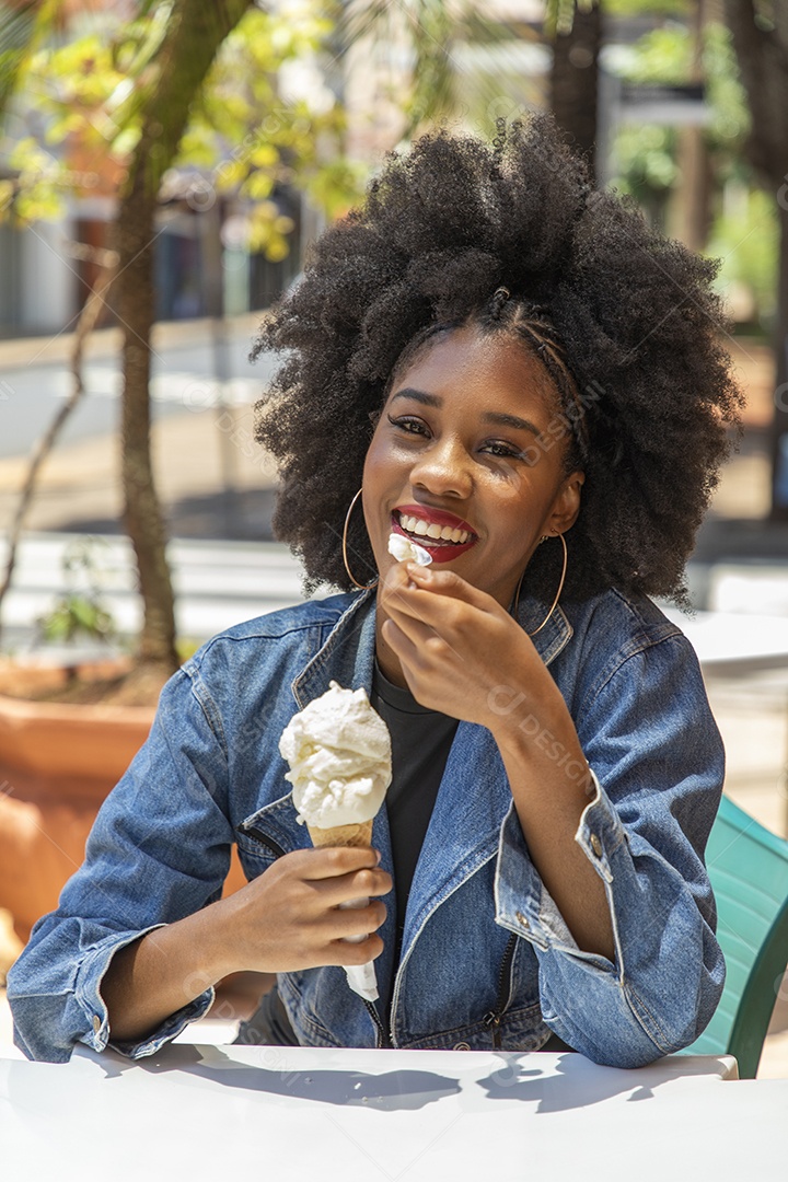 Linda mulher jovem negra cabelo afro cacheado tomando sorvete