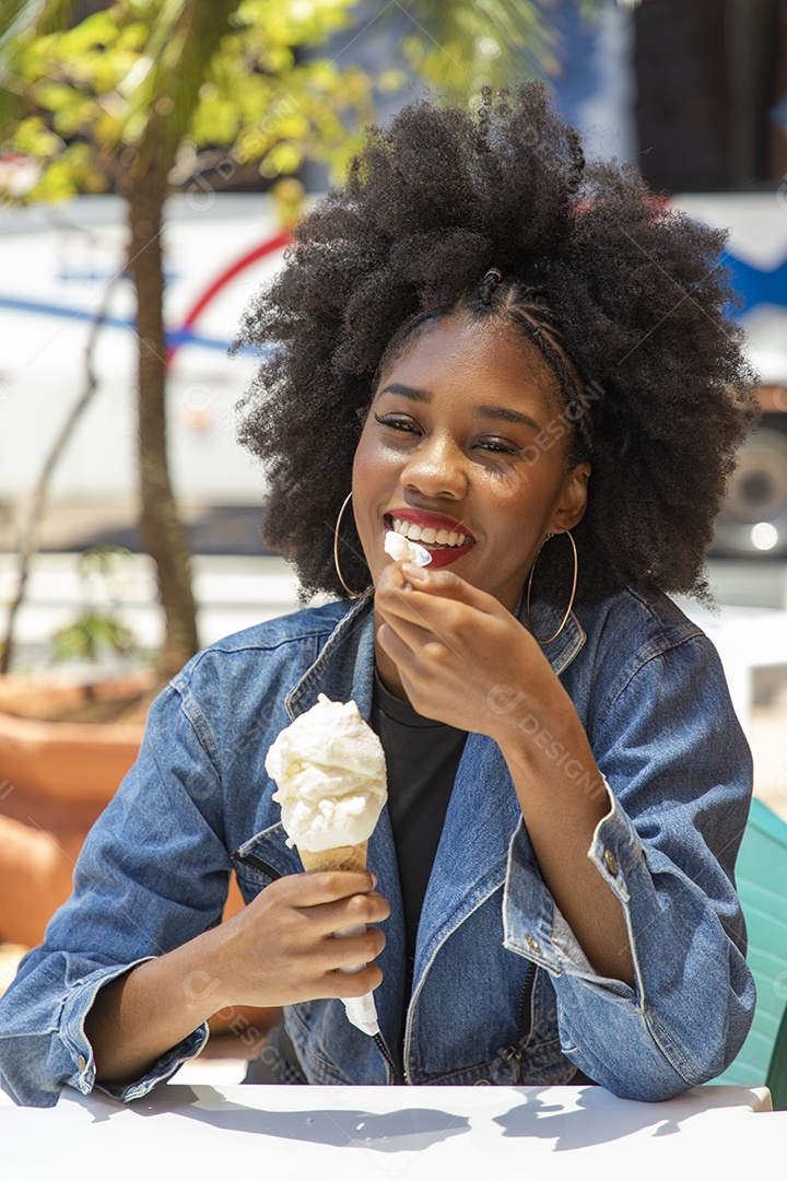 Linda mulher jovem negra cabelo afro cacheado tomando sorvete
