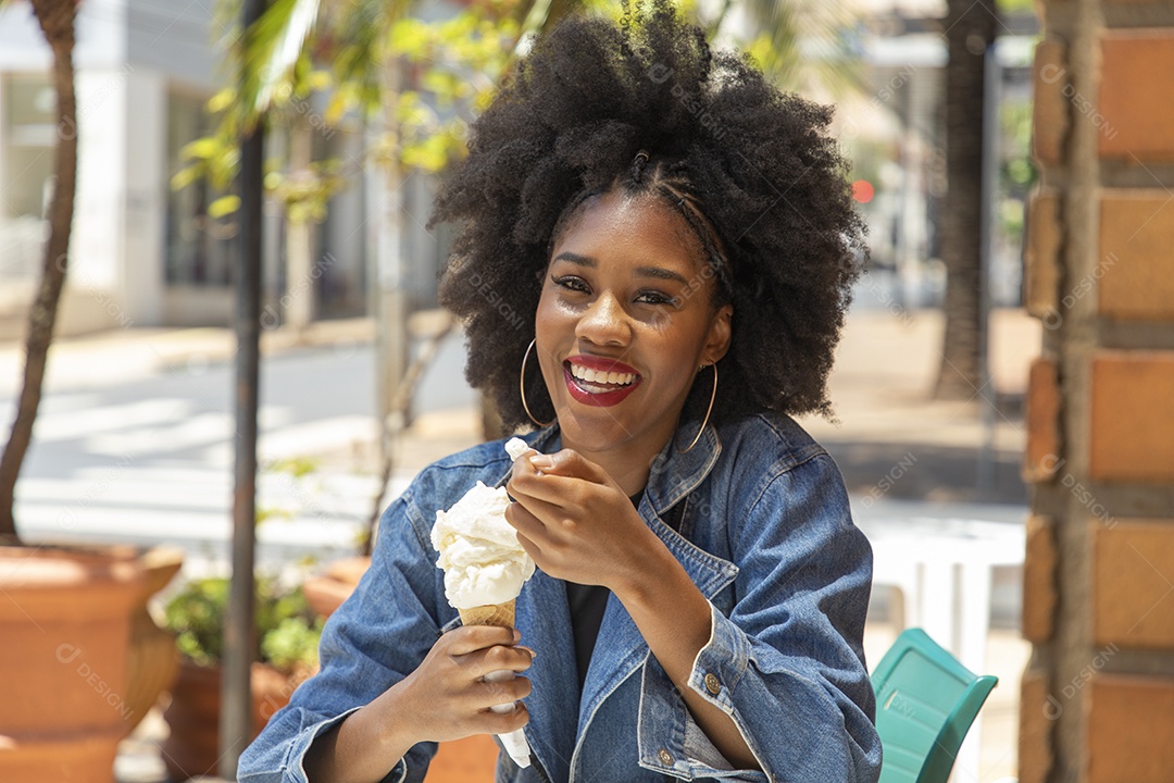 Linda mulher jovem negra cabelo afro cacheado tomando sorvete