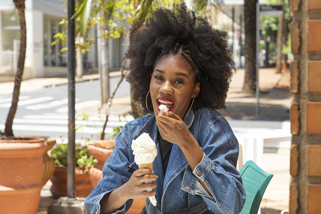 Linda mulher jovem negra cabelo afro cacheado tomando sorvete