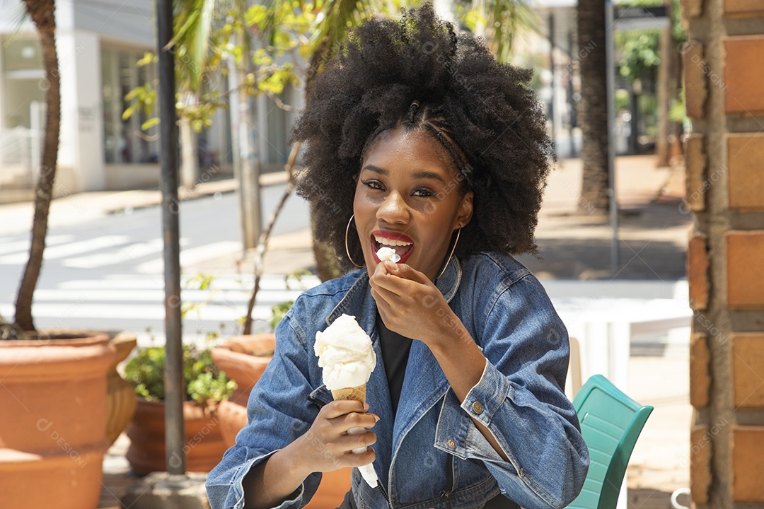 Linda mulher jovem negra cabelo afro cacheado tomando sorvete