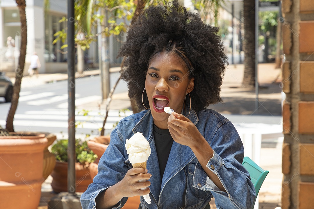 Linda mulher jovem negra cabelo afro cacheado tomando sorvete