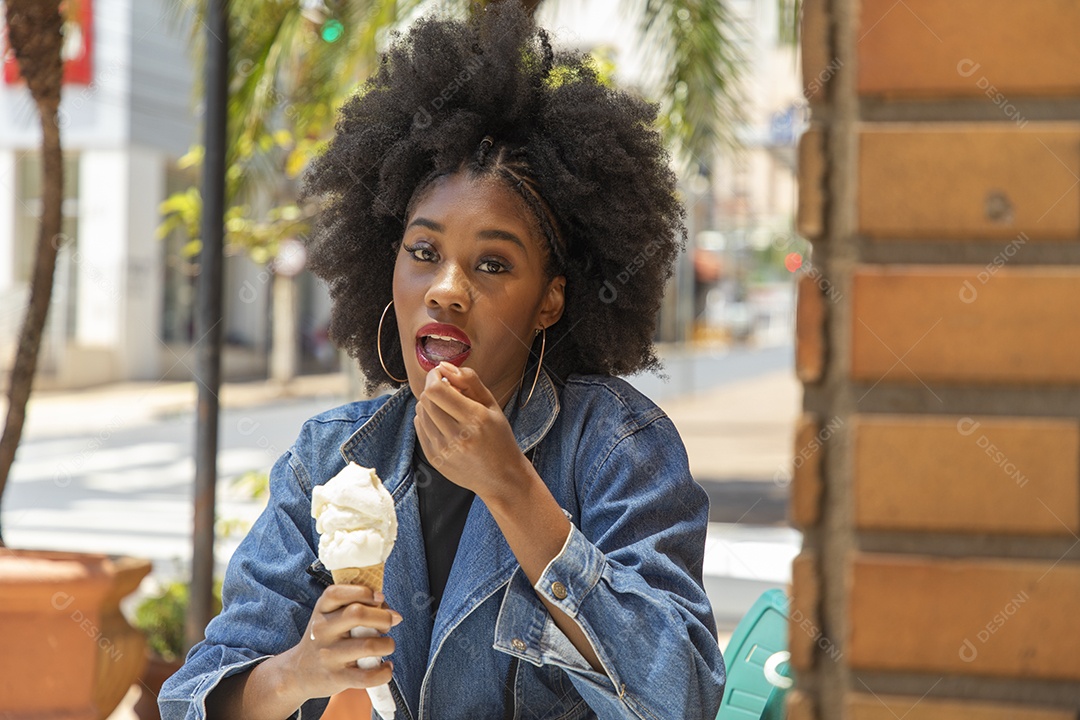 Linda mulher jovem negra cabelo afro cacheado tomando sorvete