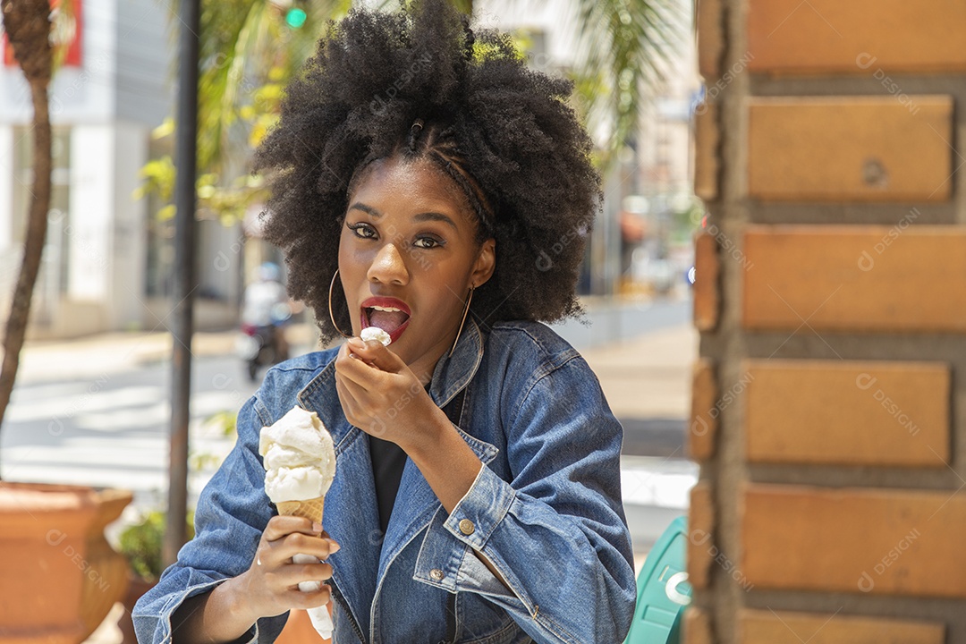 Linda mulher jovem negra cabelo afro cacheado tomando sorvete