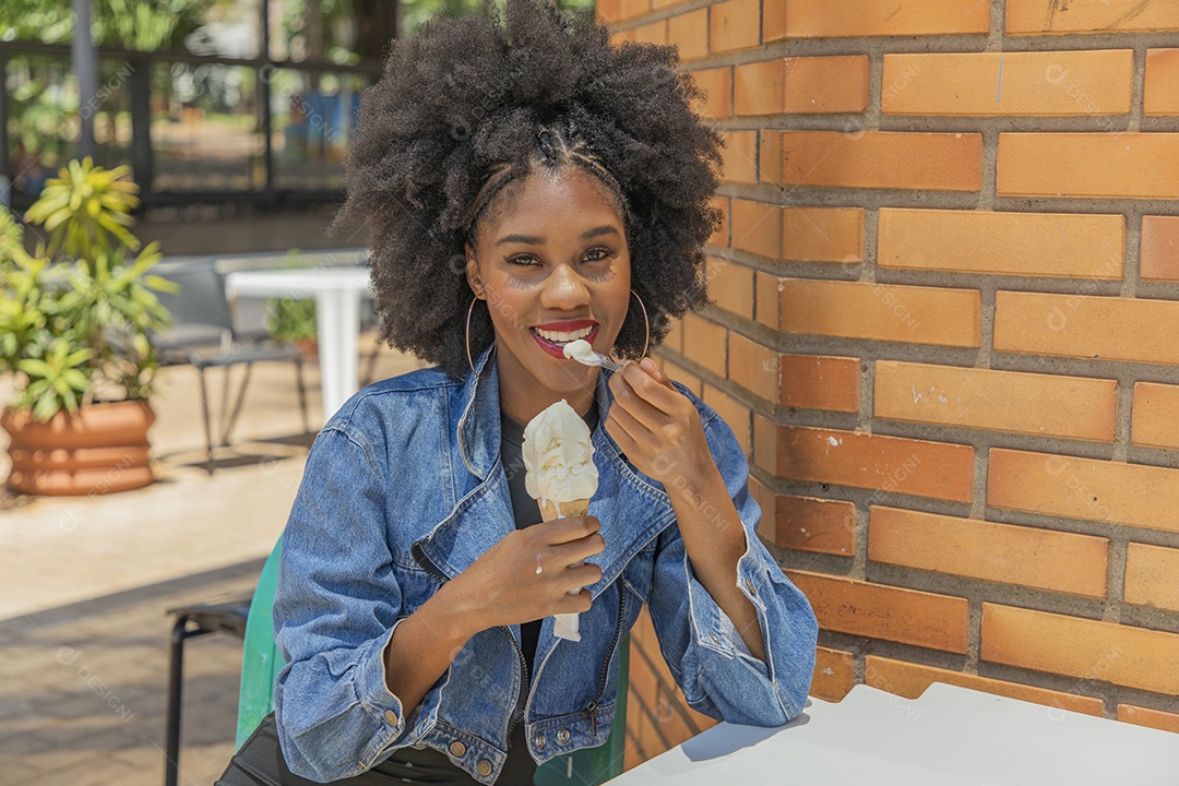 Linda mulher jovem negra cabelo afro cacheado tomando sorvete