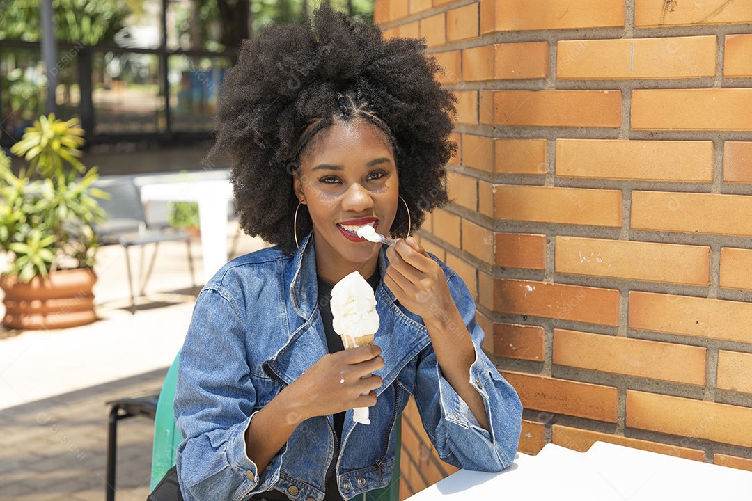 Linda mulher jovem negra cabelo afro cacheado tomando sorvete