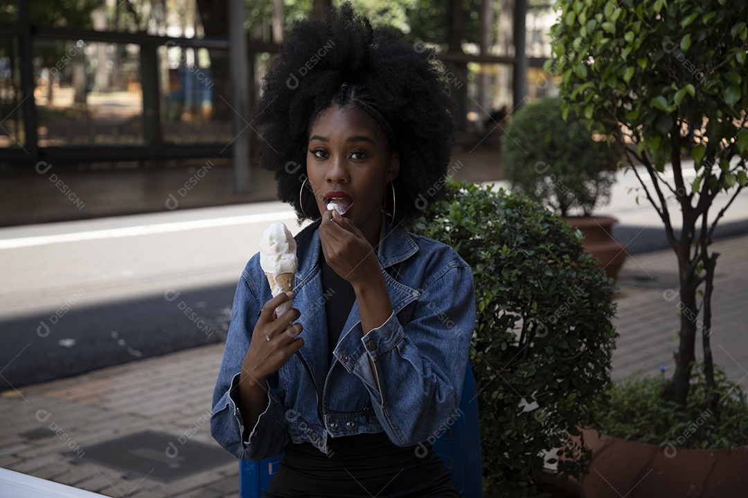 Linda mulher jovem negra cabelo afro cacheado tomando sorvete