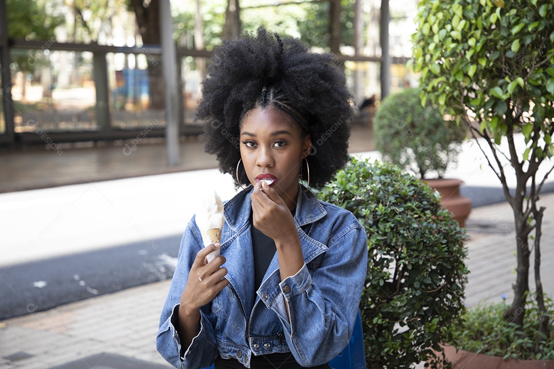 Linda mulher jovem negra cabelo afro cacheado tomando sorvete