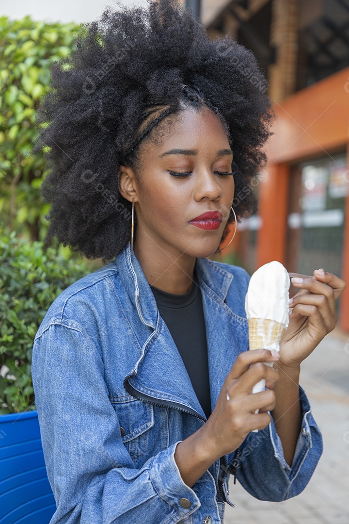 Linda mulher jovem negra cabelo afro cacheado tomando sorvete
