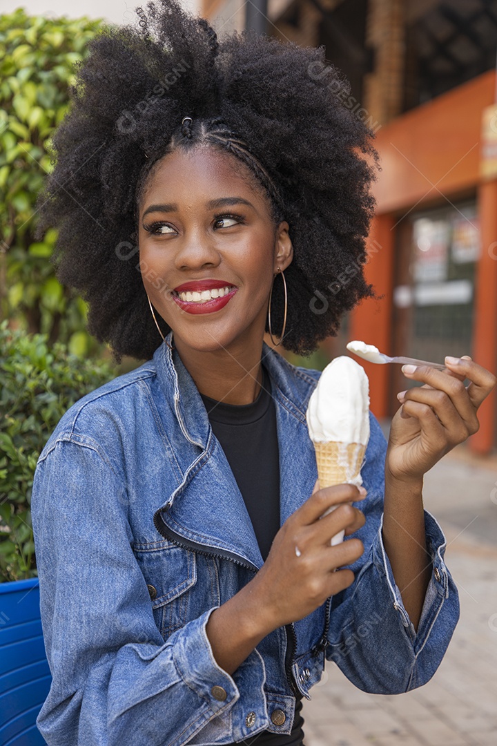 Linda mulher jovem negra cabelo afro cacheado tomando sorvete