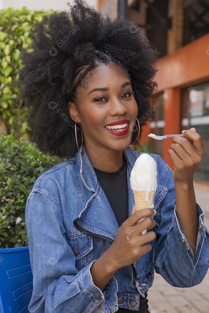 Linda mulher jovem negra cabelo afro cacheado tomando sorvete
