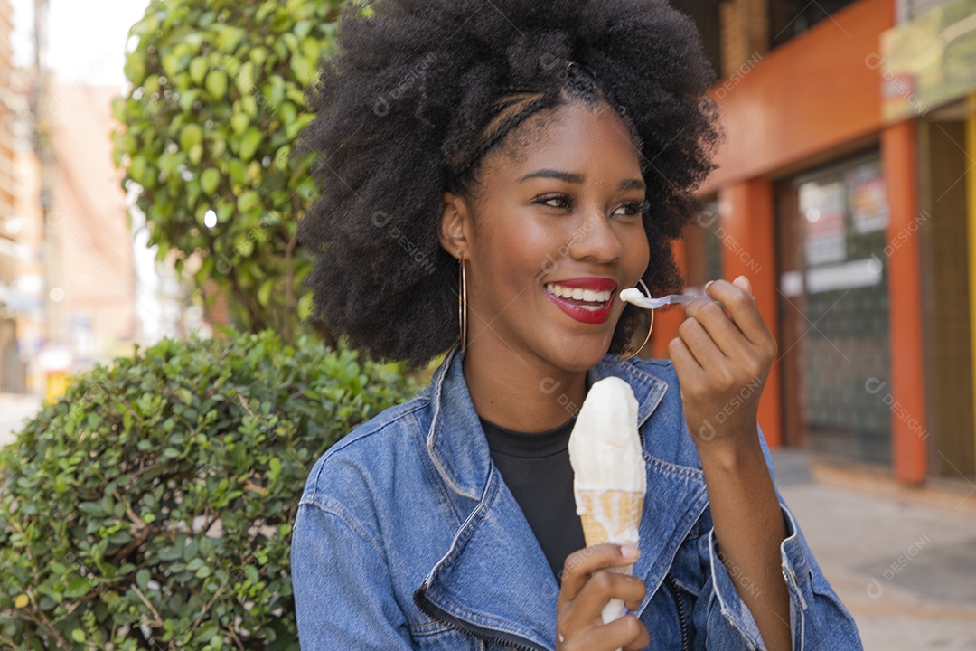 Linda mulher jovem negra cabelo afro cacheado tomando sorvete