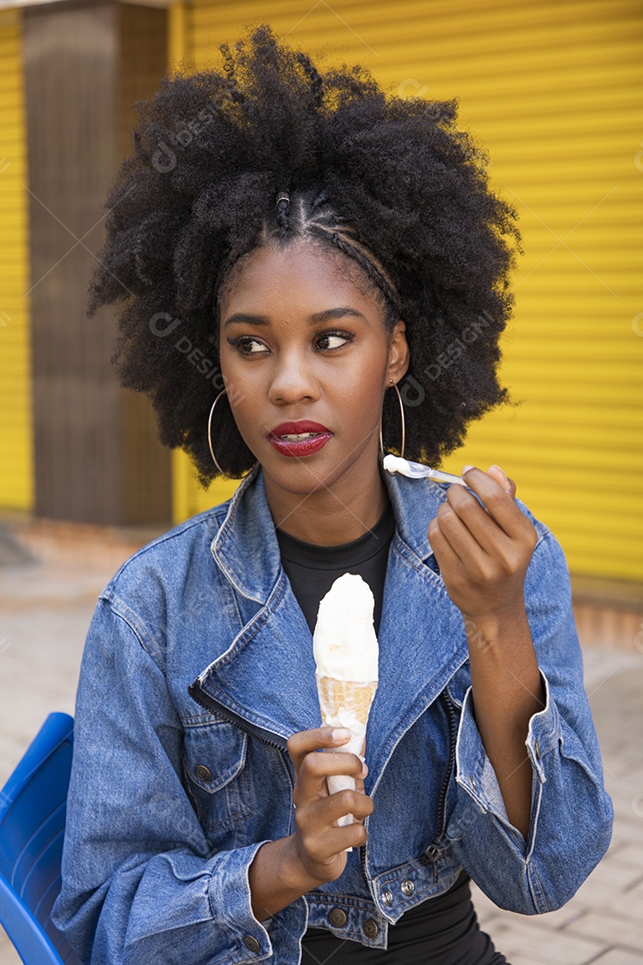 Linda mulher jovem negra cabelo afro cacheado tomando sorvete