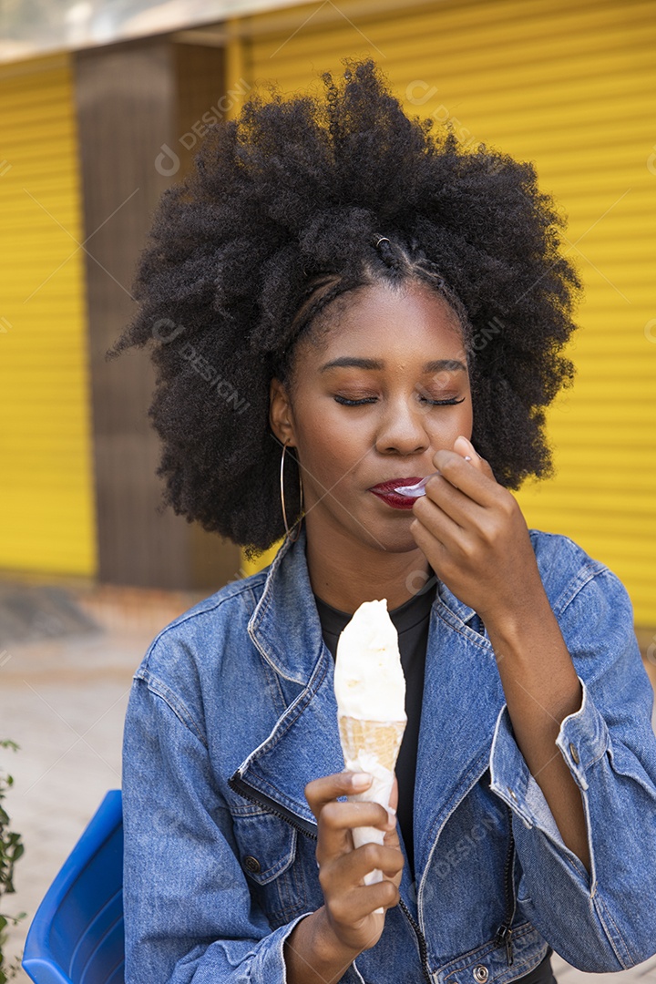 Beautiful young black woman with curly afro hair eating ice cream