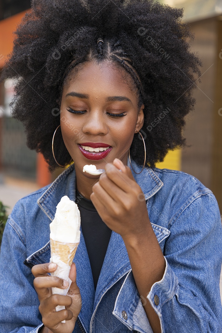Linda mulher jovem negra cabelo afro cacheado tomando sorvete