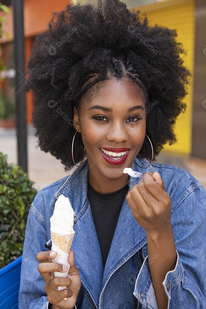 Linda mulher jovem negra cabelo afro cacheado tomando sorvete