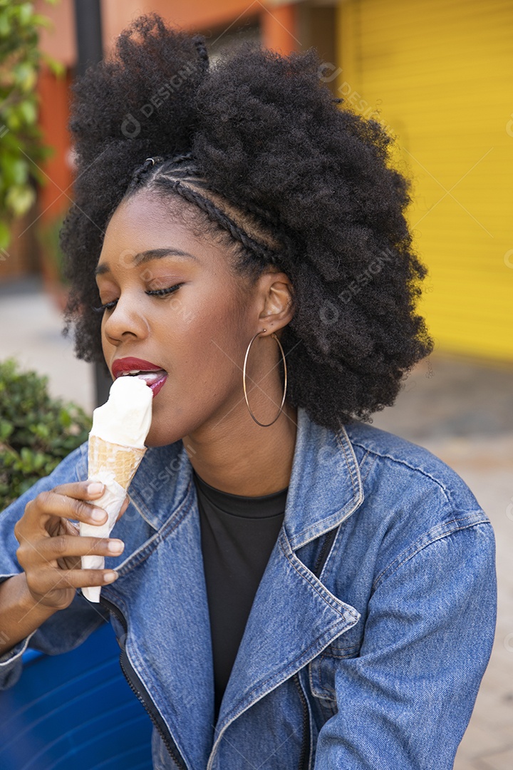 Linda mulher jovem negra cabelo afro cacheado tomando sorvete