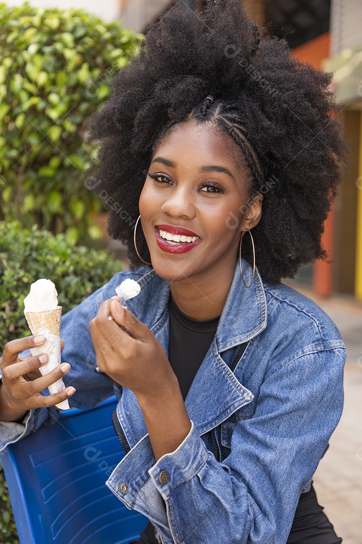 Linda mulher jovem negra cabelo afro cacheado tomando sorvete