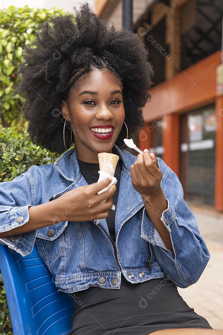 Linda mulher jovem negra cabelo afro cacheado tomando sorvete