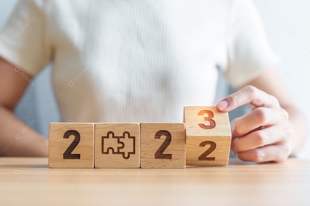 Mão de mulher mudar 2022 para 2023 bloco com ícone de quebra-cabeça.