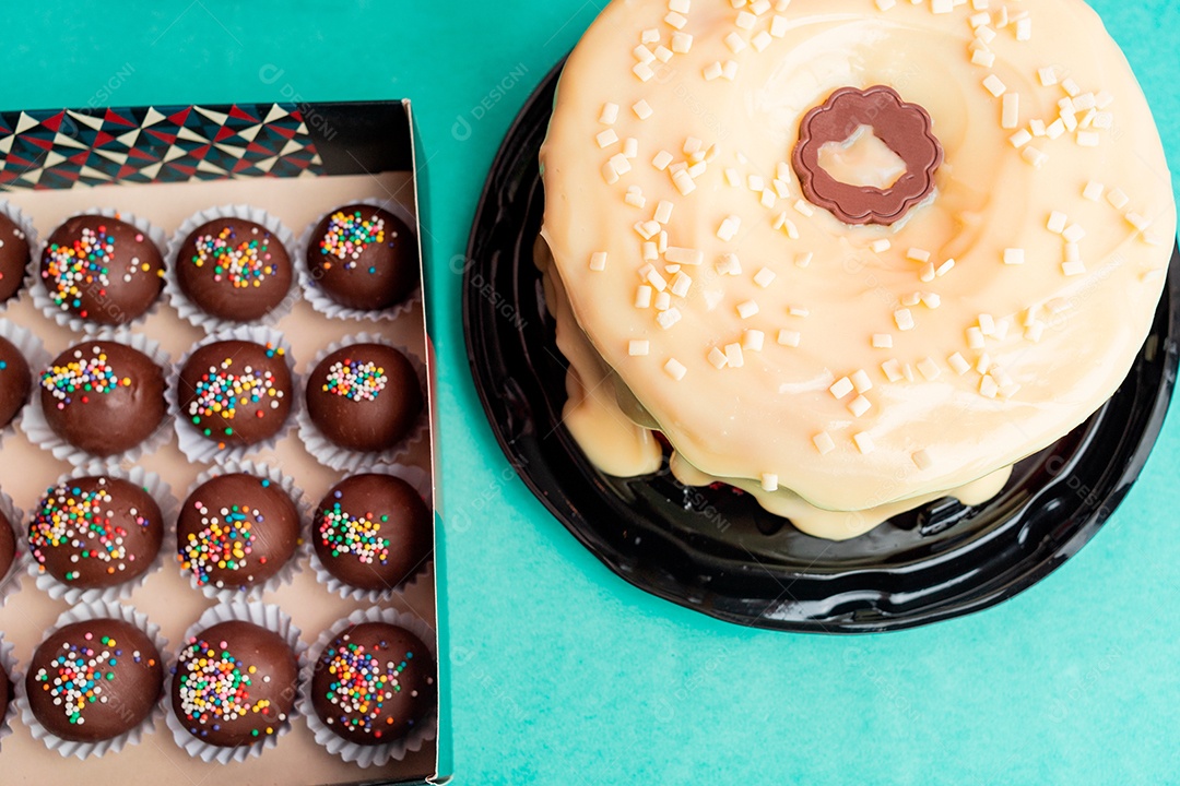 Bolos confeitados ao lado de brigadeiros doces