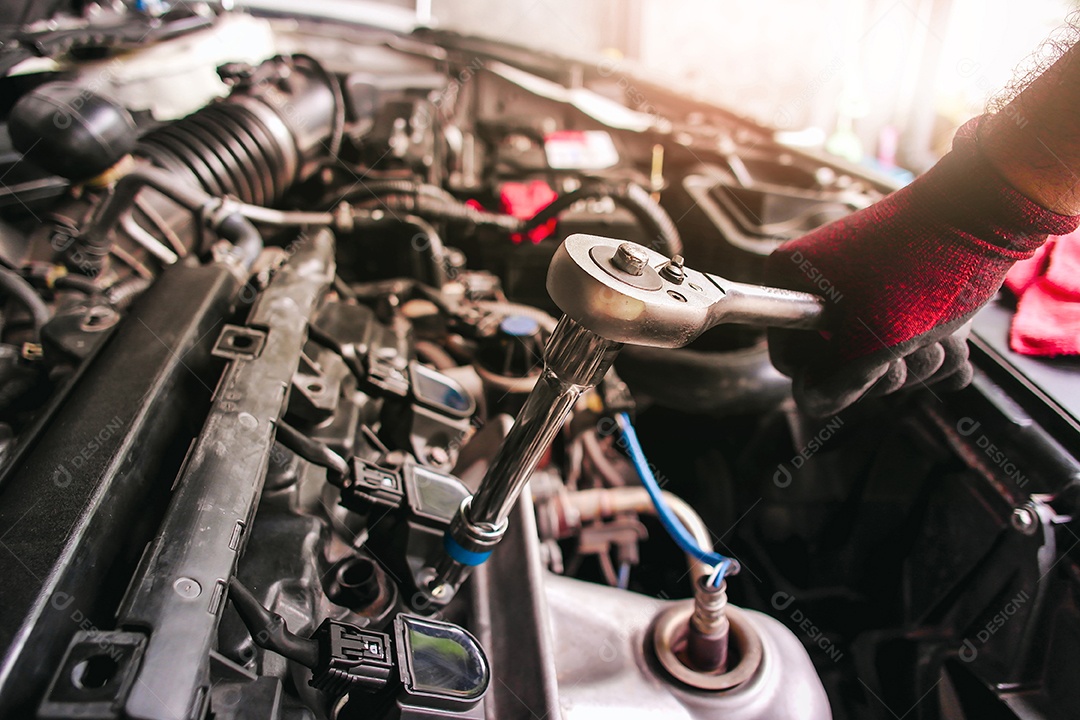 A mão enluvada vermelha do mecânico de automóveis está prendendo o parafuso