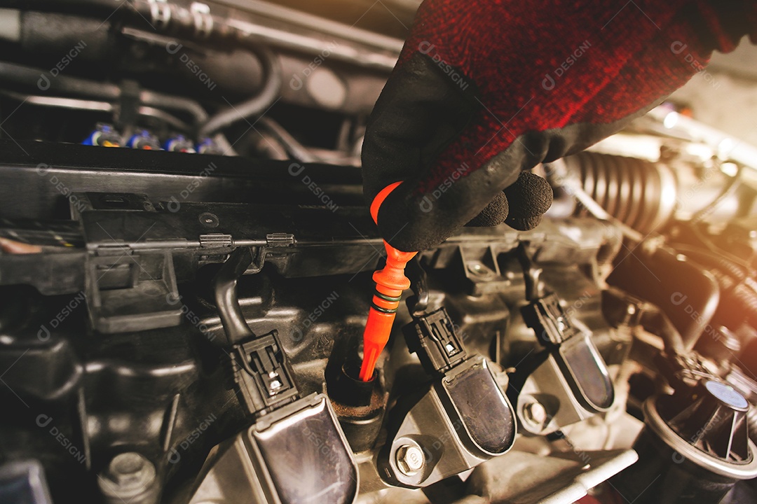 Um mecânico está puxando a vareta laranja para verificar o nível do óleo