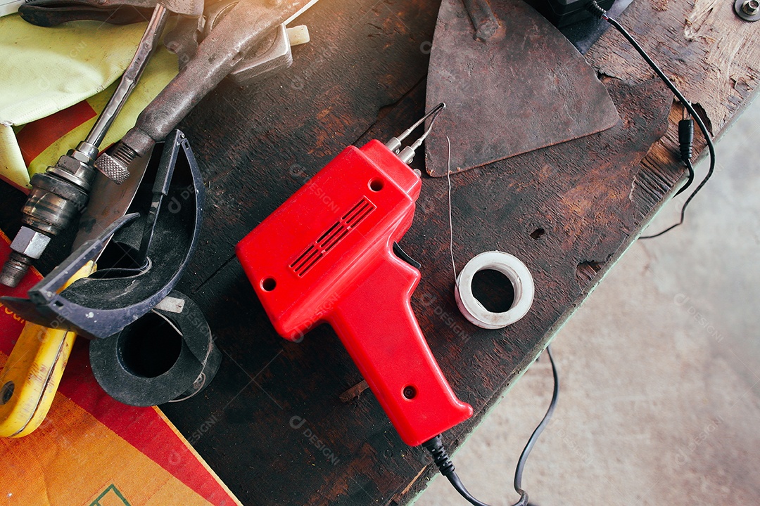 Ferro de solda elétrico vermelho com chumbo em um velho mecânico de madeira