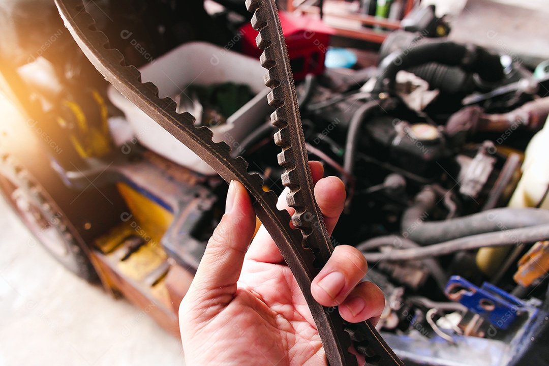 Uma mão mecânica segurando uma correia dentada com um motor de carro