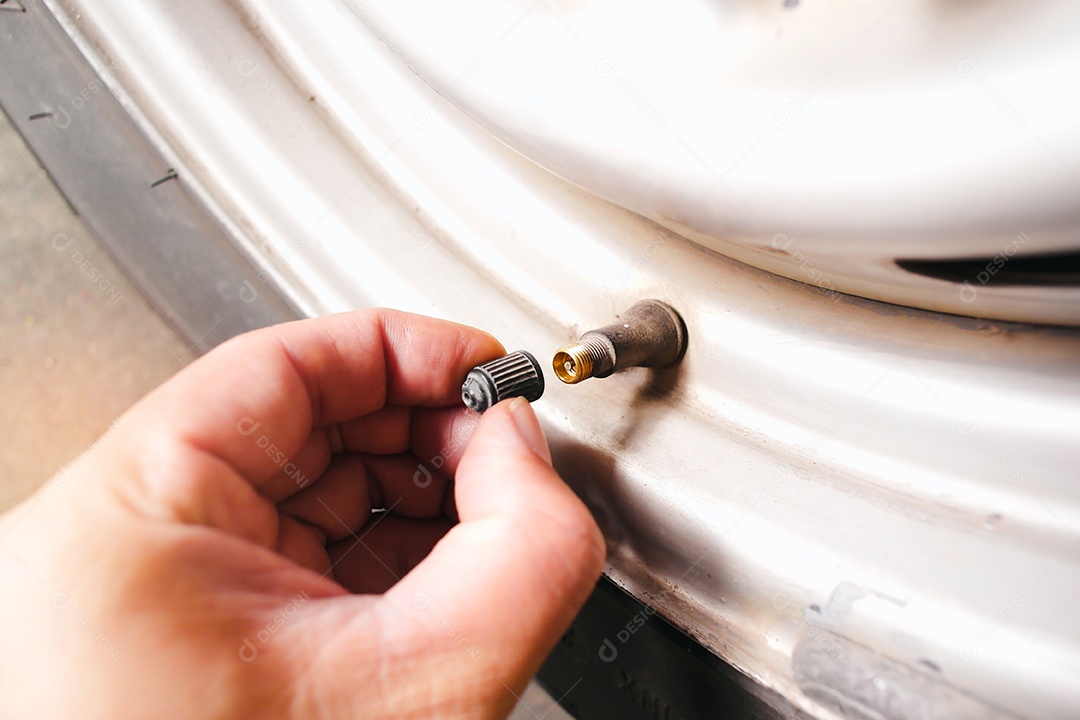 O motorista do carro remove manualmente a tampa da válvula do pneu