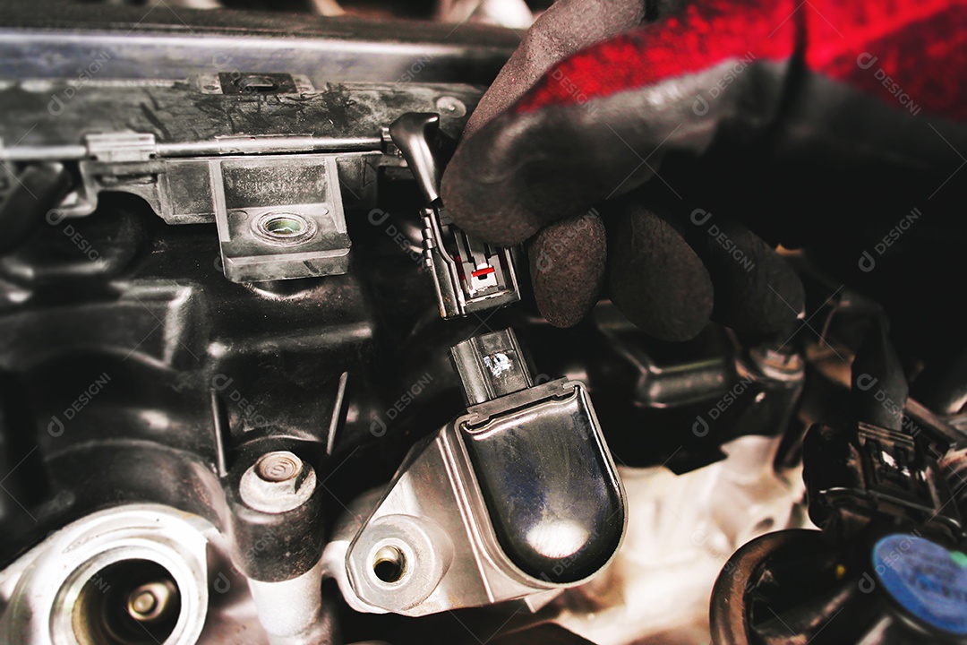 O mecânico de automóveis está desconectando a bobina de ignição do carro