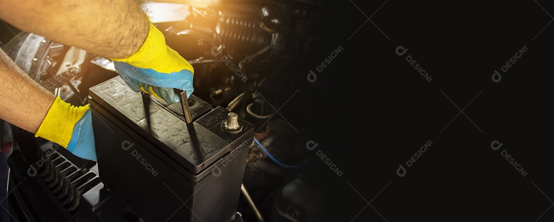 O mecânico de automóveis está substituindo a bateria no compartimento do motor