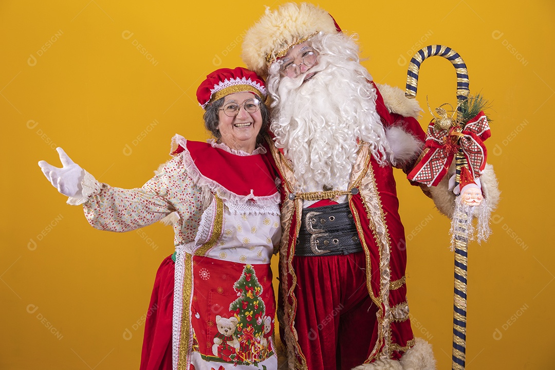 Lindo Casal Papai Noel ao lado de Mamãe Noel sobre fundo isolado amarelo