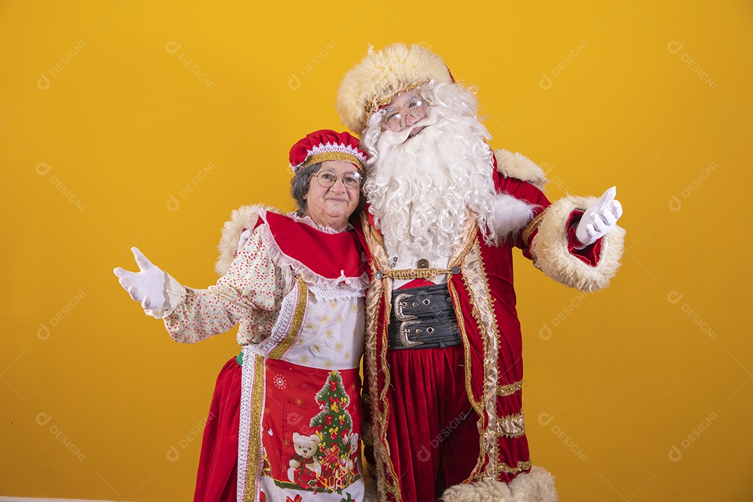 Lindo Casal Papai Noel ao lado de Mamãe Noel sobre fundo isolado amarelo