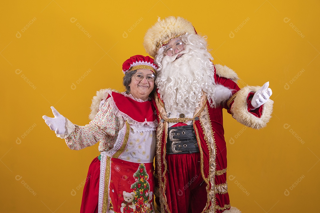 Lindo Casal Papai Noel ao lado de Mamãe Noel sobre fundo isolado amarelo