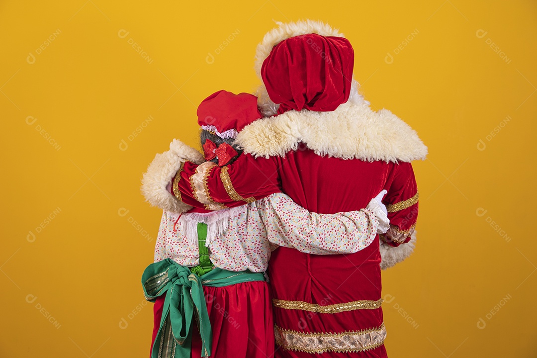 Lindo Casal Papai Noel ao lado de Mamãe Noel sobre fundo isolado amarelo