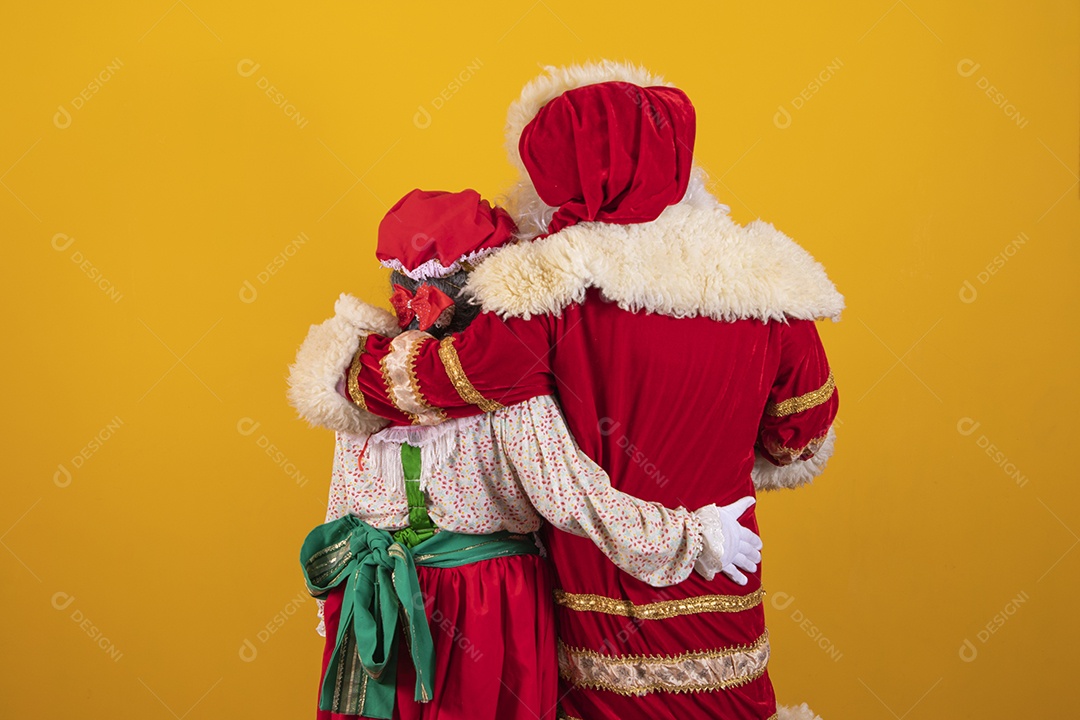 Lindo Casal Papai Noel ao lado de Mamãe Noel sobre fundo isolado amarelo