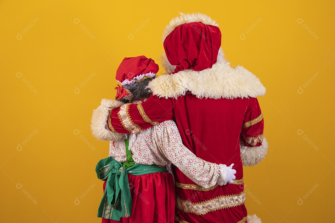 Lindo Casal Papai Noel ao lado de Mamãe Noel sobre fundo isolado amarelo