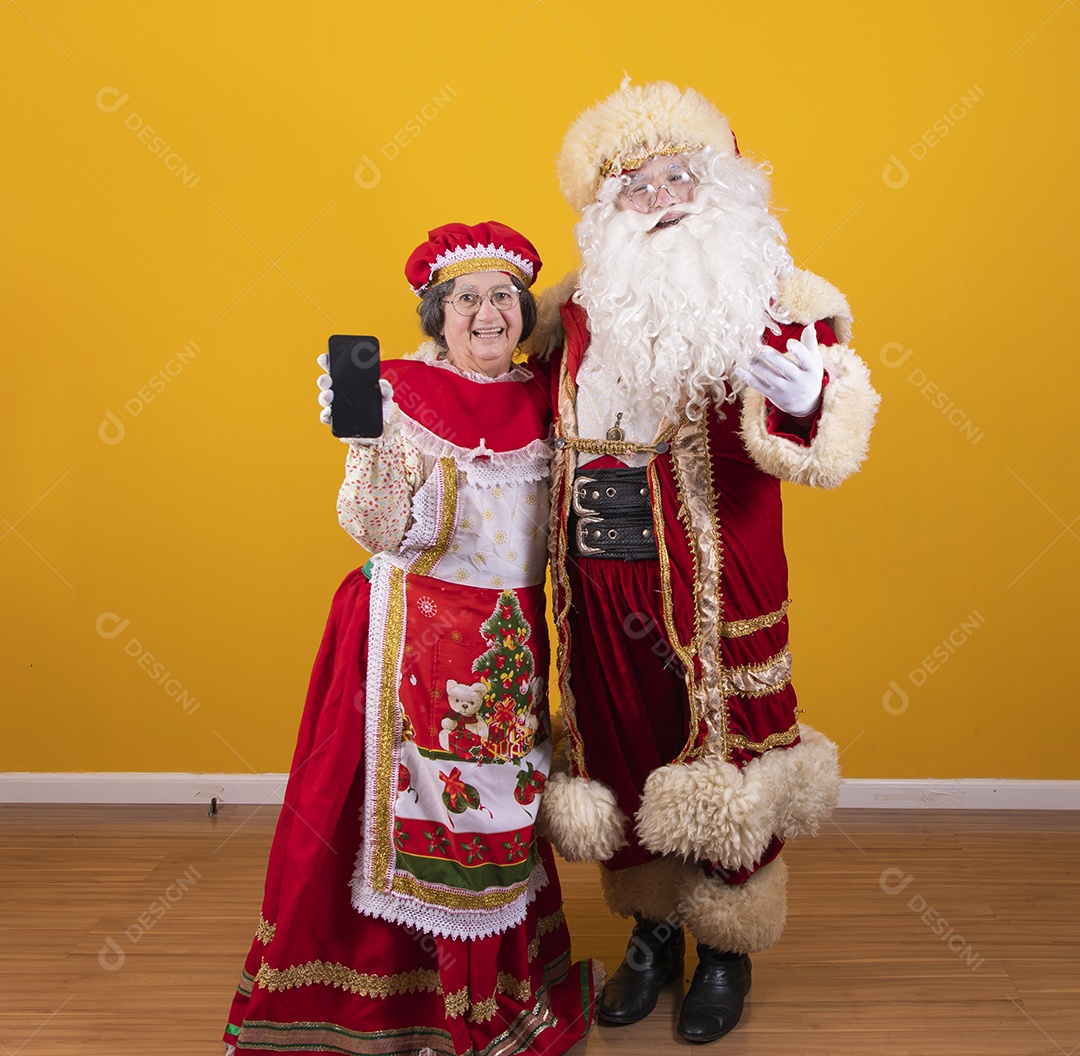 Lindo Casal Papai Noel ao lado de Mamãe Noel sobre fundo isolado amarelo
