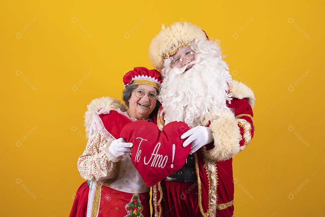 Lindo Casal Papai Noel ao lado de Mamãe Noel sobre fundo isolado amarelo