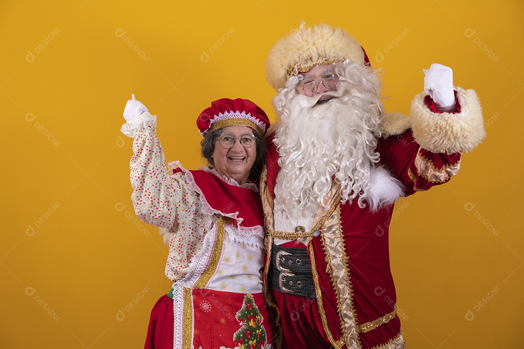 Lindo Casal Papai Noel ao lado de Mamãe Noel sobre fundo isolado amarelo