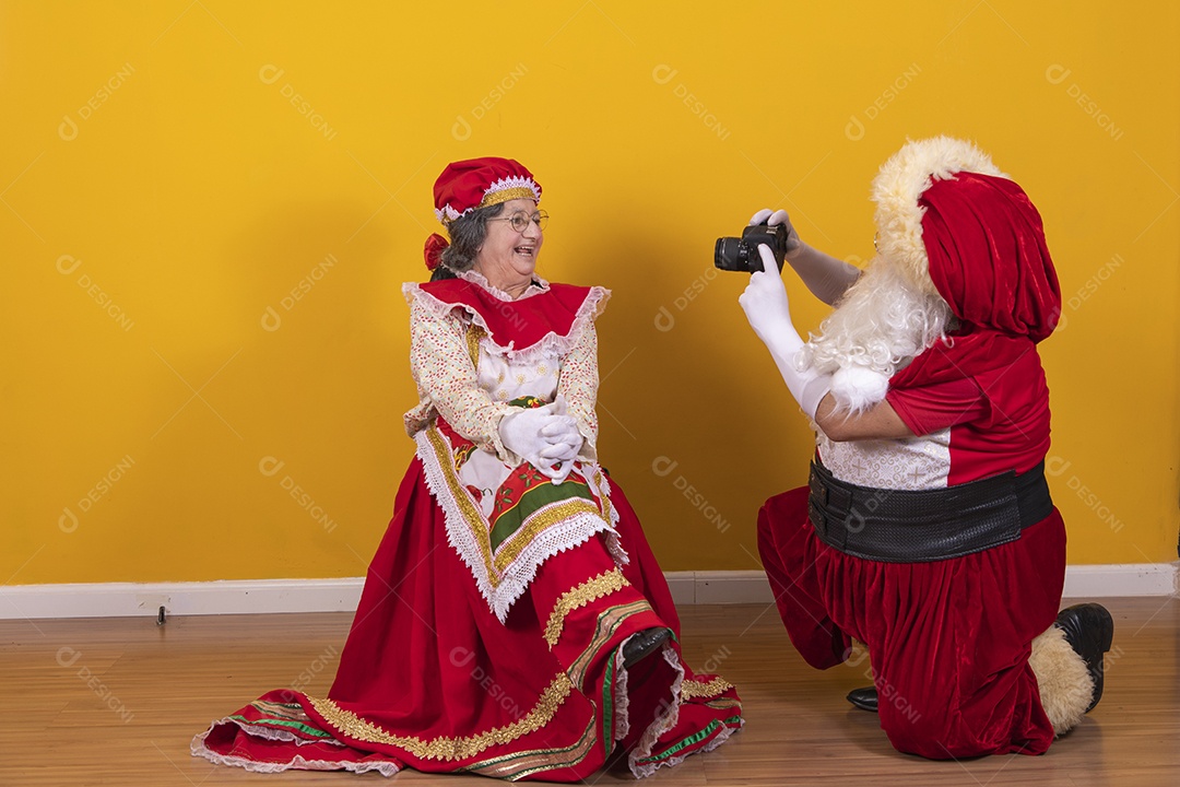 Papai Noel ao lado de Mamãe Noel sobre fundo isolado amarelo