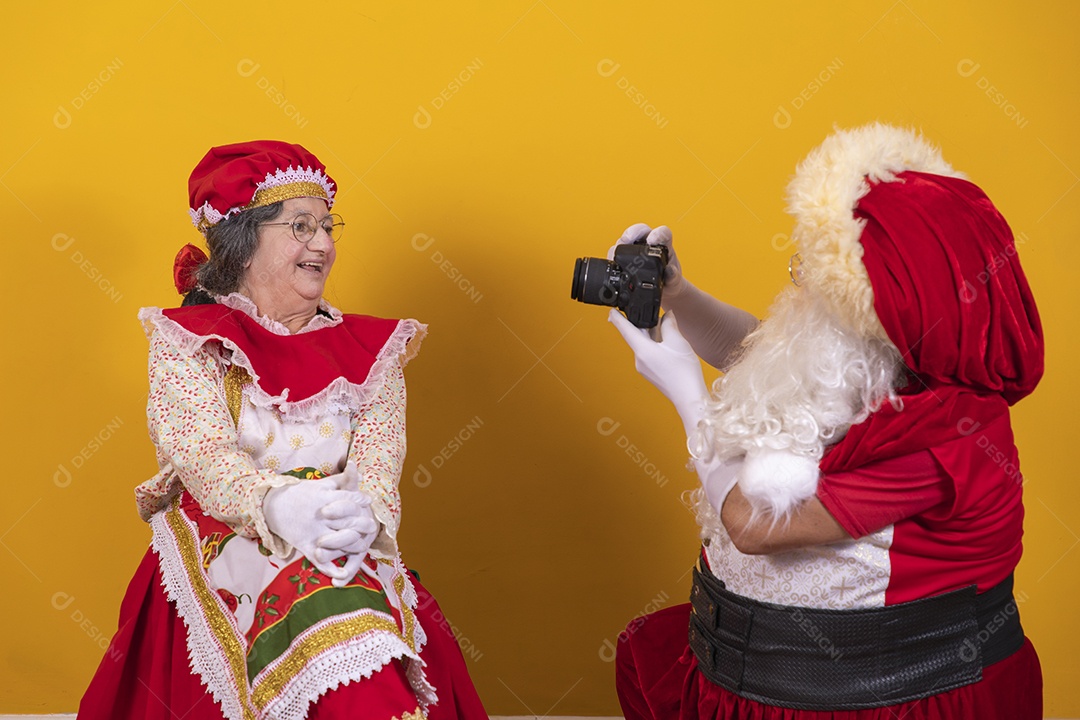 Papai Noel ao lado de Mamãe Noel sobre fundo isolado amarelo
