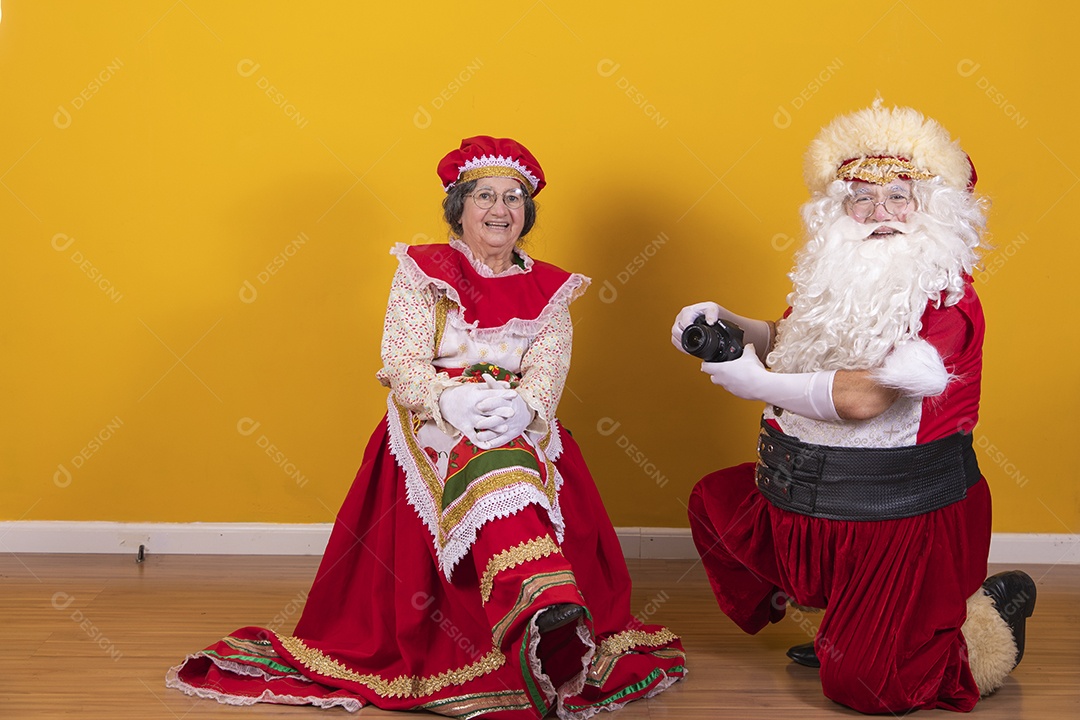 Papai Noel ao lado de Mamãe Noel sobre fundo isolado amarelo