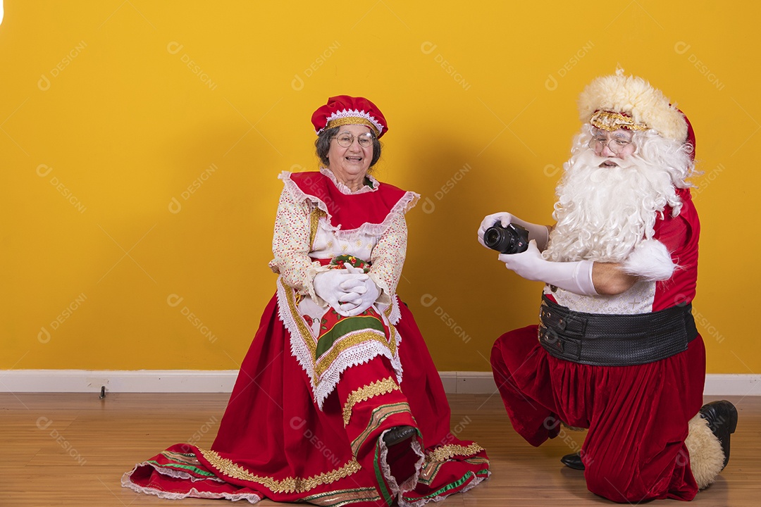 Papai Noel ao lado de Mamãe Noel sobre fundo isolado amarelo