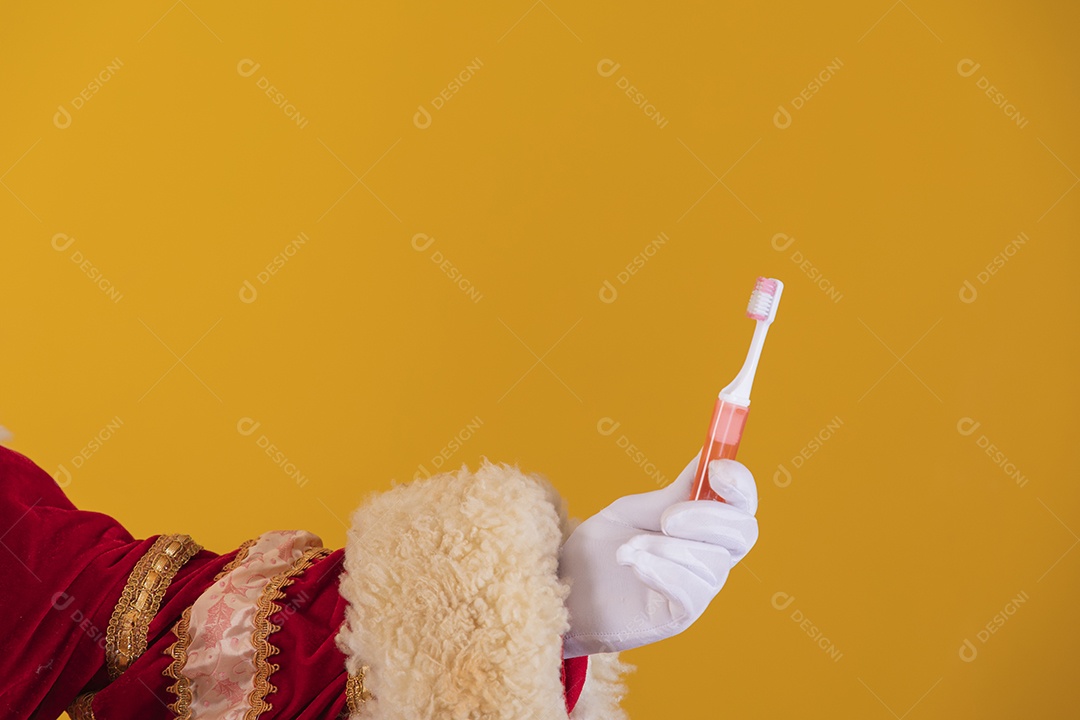 Papai Noel segurando escovas de dente sobre fundo amarelo